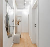 A bright hallway with a mirror, a bench, and a wooden decor floor in a 3-room apartment.