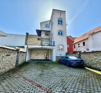 The building on Dolná Street 28 in Banská Bystrica with a parking lot and a stone wall.