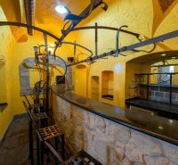 The interior of the building with yellow walls, a stone bar, and metal chairs.