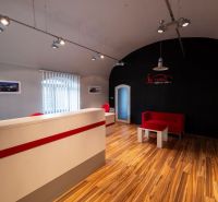 Reception with a wooden decor floor. Red elements on a dark wall. Building.