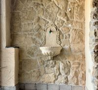 Stone wall with a decorative fountain and a faucet.