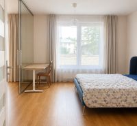 Bedroom in a 2-room apartment with a bed, table, curtains, and a floor with a wooden decor.