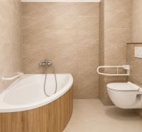 Bathroom with a bathtub and toilet in a 2-room apartment, tiles in a beige shade.