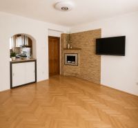 A room with a TV on the wall, a fireplace, and a wooden decor floor.