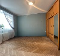 A room with a wooden decor floor, a wardrobe, and curtains in a two-room apartment.