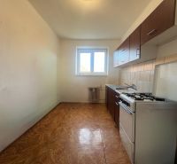 A kitchen in a 2-room apartment with a gas stove and a window, flooring with a wooden decor.