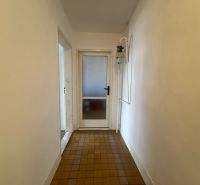 A hallway in a 2-room apartment with tiles and white walls.