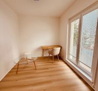 A room in a 3-room apartment with a wooden decor floor, a table, and a chair.