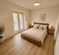 A bedroom in a 3-room apartment with a wooden decor floor and a potted plant.