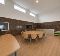An office with a wood-patterned floor, a round table, and cabinets in the production area.