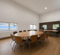 Conference room with a large table, chairs, and office desks, floor with wooden decor.