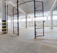 A fenced interior of a warehouse and hall with open gates and bright walls.