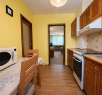 A kitchen with a microwave and a wooden decor floor in a 2-room apartment.