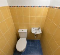 Toilet with a sink in a bathroom with colorful tiles in a 2-room apartment.