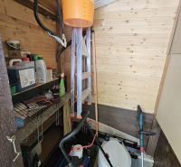 There is a shed in the garden with tools and shelves for storage.