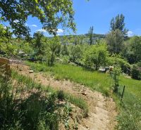 A sloped garden with a view in Budatín, Budatín, surrounded by lush greenery and a blue sky.