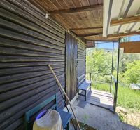A cottage in Budatín with wooden cladding, a terrace, and a view of the green garden.