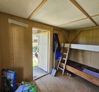 A room in a cottage with a bunk bed and a wooden decor floor.