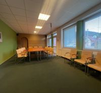 Room with a conference table and chairs, large windows, wooden decor flooring.