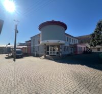 Production premises in Kremnička, Banská Bystrica surrounded by a paved courtyard and trees.