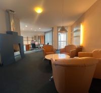 Interior of manufacturing spaces with a fireplace, leather armchairs, and a coffee table.