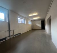 A long room with white walls, windows, and cast iron radiators in warehouses and halls.