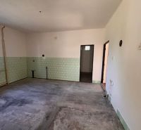 A room in a family house with an unfinished floor and green tiles.