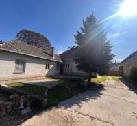 A family house in Vrakúňa with a concrete yard and a large coniferous tree.
