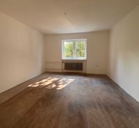 A spacious room in a family house with a wooden decor floor and a large window.