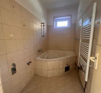 A bathroom in a family house with a corner bathtub and a radiator on the wall.