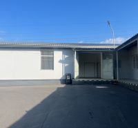 In the area of warehouses and halls in the Banská Bystrica district, in front of a white building with doors.