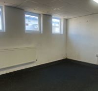 A room with windows, a radiator, and a rubber floor in a warehouse and halls.