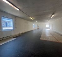 The interior photograph depicts an empty space with a black floor and windows, warehouses and halls.