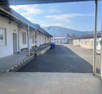Industrial buildings and warehouses on Cementárenská Road, in Senica, surrounded by mountains.