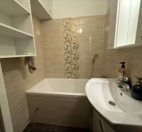 A bathroom with a bathtub in a 4-room apartment, with storage shelves and decorative tiles.