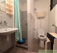 A bathroom in a cottage with a toilet, sink, and shower with a turquoise curtain.