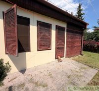 A cottage in Nové Zámky with wooden shutters and a landscaped garden.