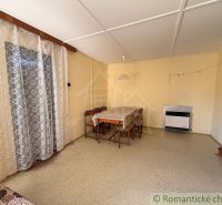 A dining room in a cottage with a wooden decor floor and curtains.