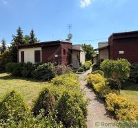 Garden cottages surrounded by greenery in the town of Nové Zámky under a blue sky.