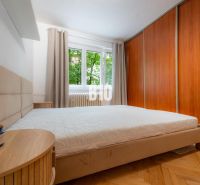 A bedroom in a two-room apartment with a wooden decor floor and a built-in wardrobe.