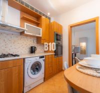 A kitchen with a gas stove, dishwasher, and bar table in a 2-room apartment.