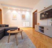 Living room with a TV on the wall, a gray sofa, and a floor with a wood decor.