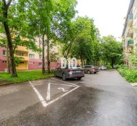 A parking lot with cars and residential buildings surrounded by greenery in Martin.