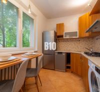 A kitchen in a 2-room apartment with a wooden decor and appliances, beautifully illuminated.