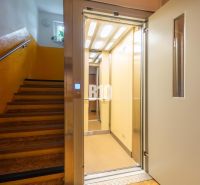A staircase of a building with an open elevator and yellow walls in an apartment building.