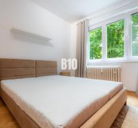 A bedroom in a 2-room apartment with a large window and a floor with a wood decor.