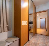 Entrance hallway with a coat rack, mirrored wardrobe, and wooden decor flooring in a 2-room apartment.
