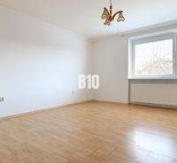 A spacious room with white walls in a family house and a floor with a wooden decor.