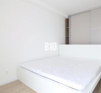 Bright bedroom in a 2-room apartment with a bed and built-in wardrobe, floor with wood decor.