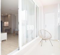 A balcony with transparent railings and a view of the interior of a 2-room apartment.